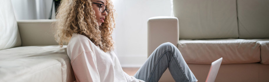 cheerful young lady working on her computer to find cheap car insurance with Geico