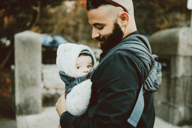 Man carrying a baby in a carrier, highlighting bundle and save insurance option.
